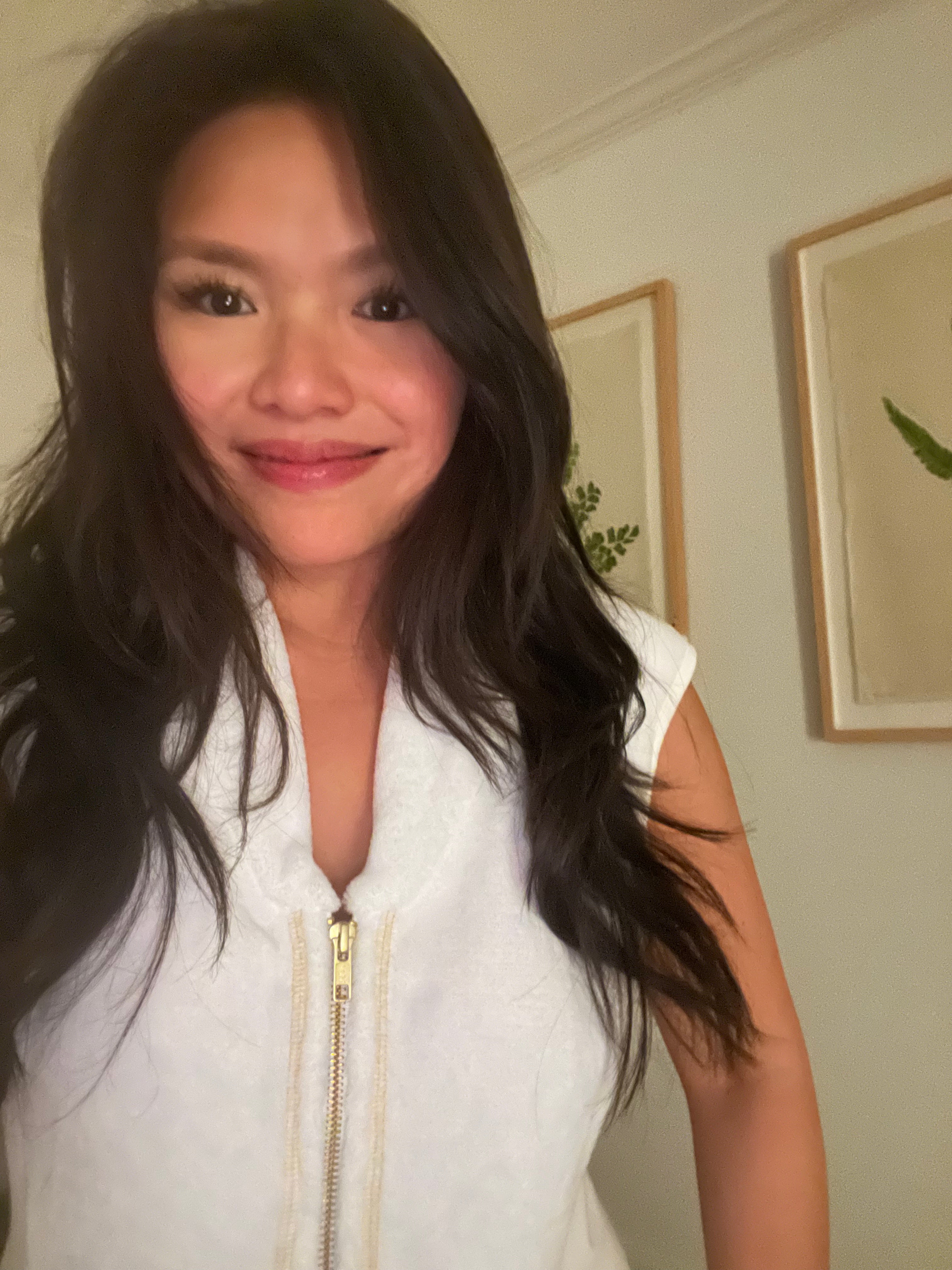 A woman with dark hair wearing a white zip-up robe, as she gets ready