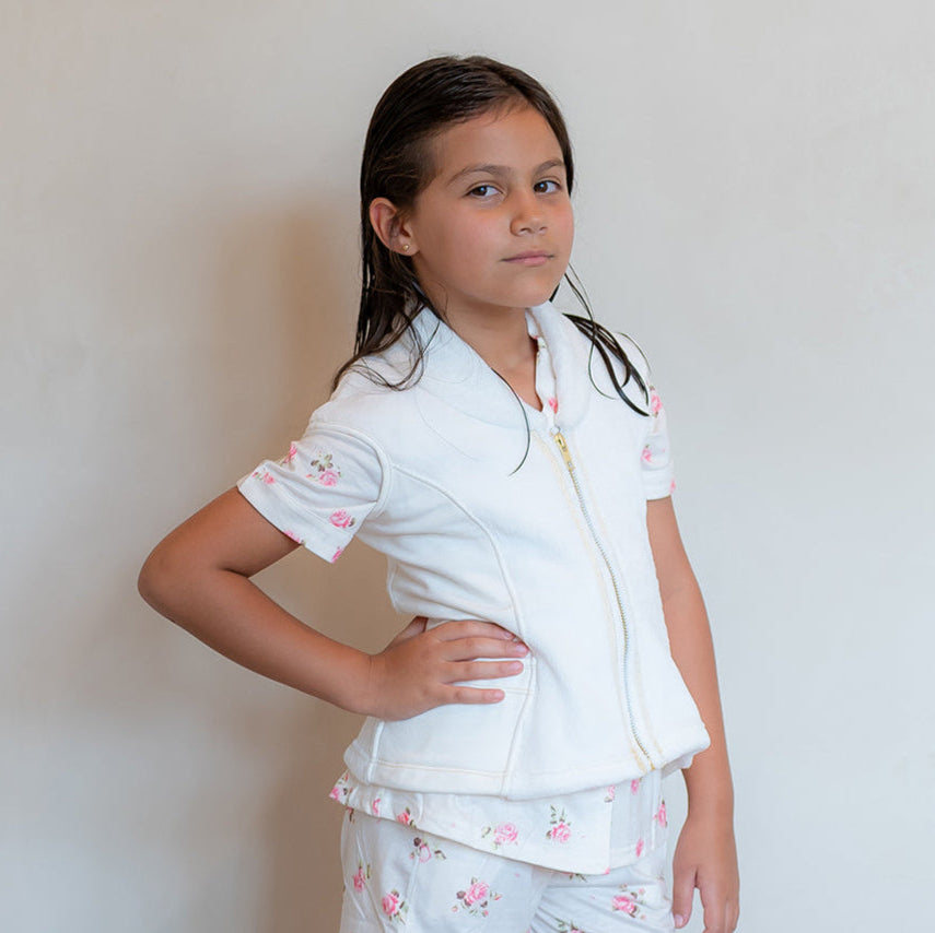 Young girl wearing a Post shower vest with a pijama floral patterns against a plain background