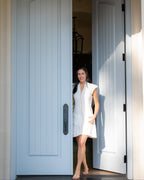 Woman in a post shower dress standing in an open door with a light blue door.