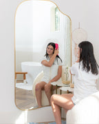 Woman brushing wet hair in front of a large mirror wearing a post shower vest as a luxury robe alternative